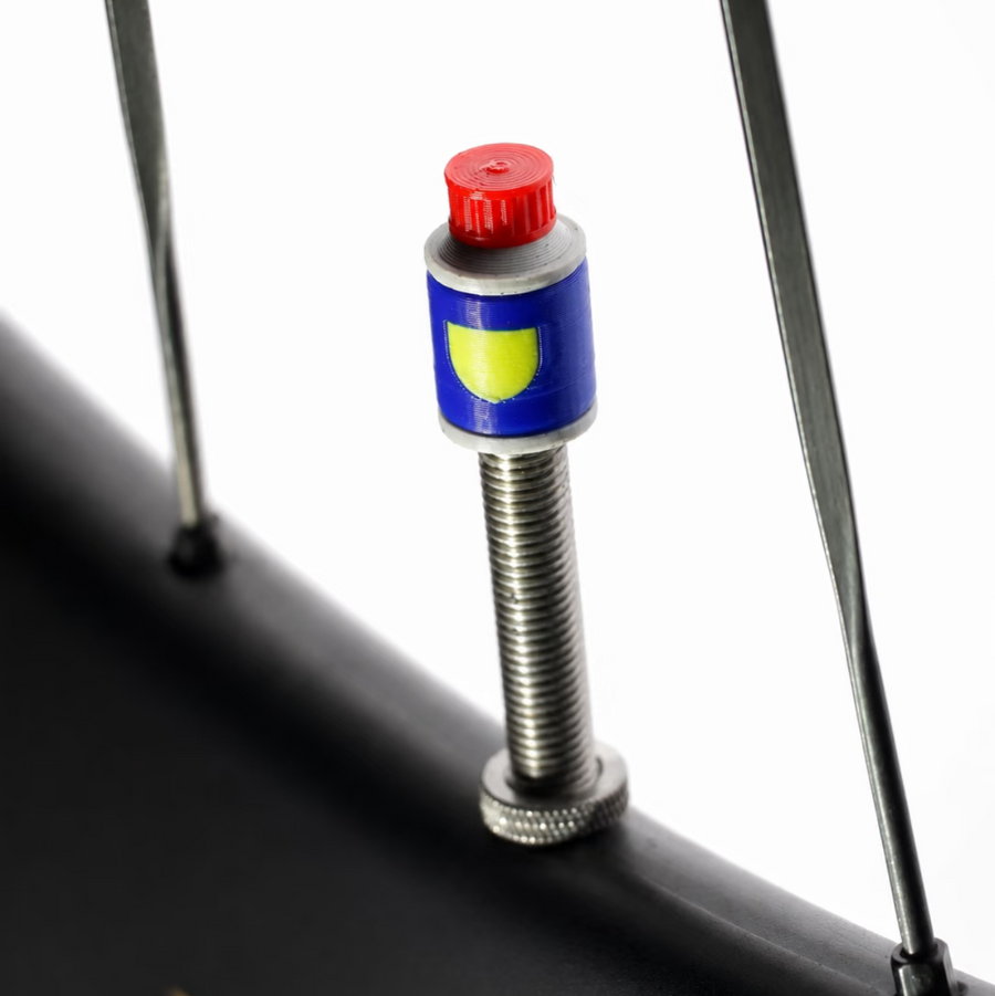 Tiny Detour Blue Cologne valve cap installed on a bicycle wheel